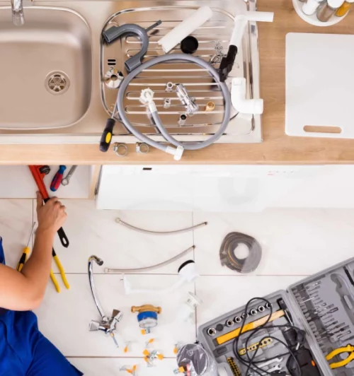 plumber under the kitchen sink fixing plumbing issue with a bunch of plumbing tools brandon ms